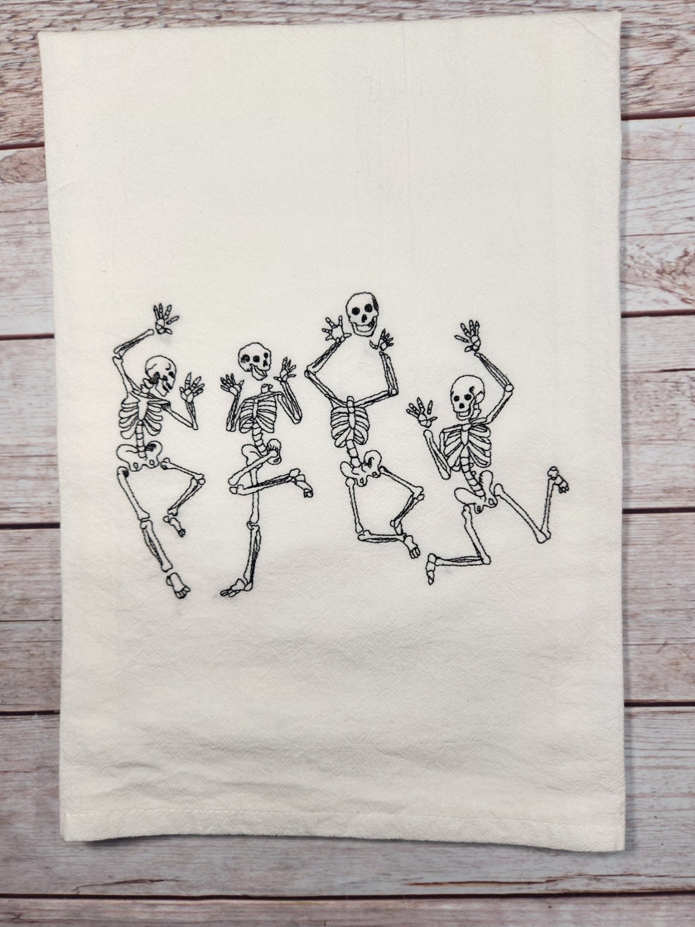 White towel with black skeleton designs on a wooden surface